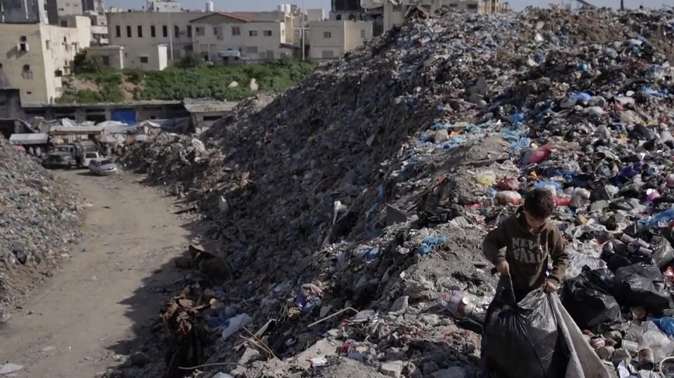 Ein Junge sammelt Müll in Gaza.