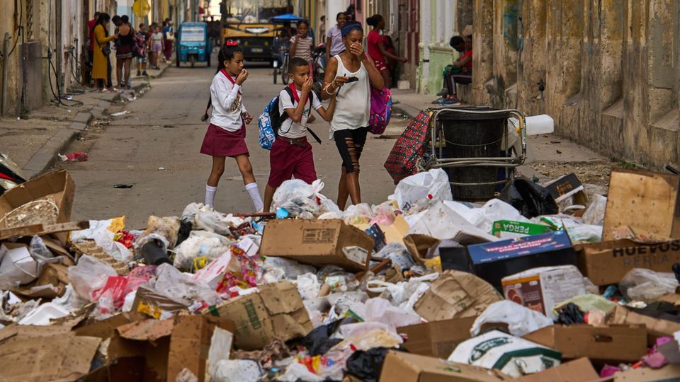 Kinder halten sich die Nase zu, während sie an Müllbergen vorbeigehen