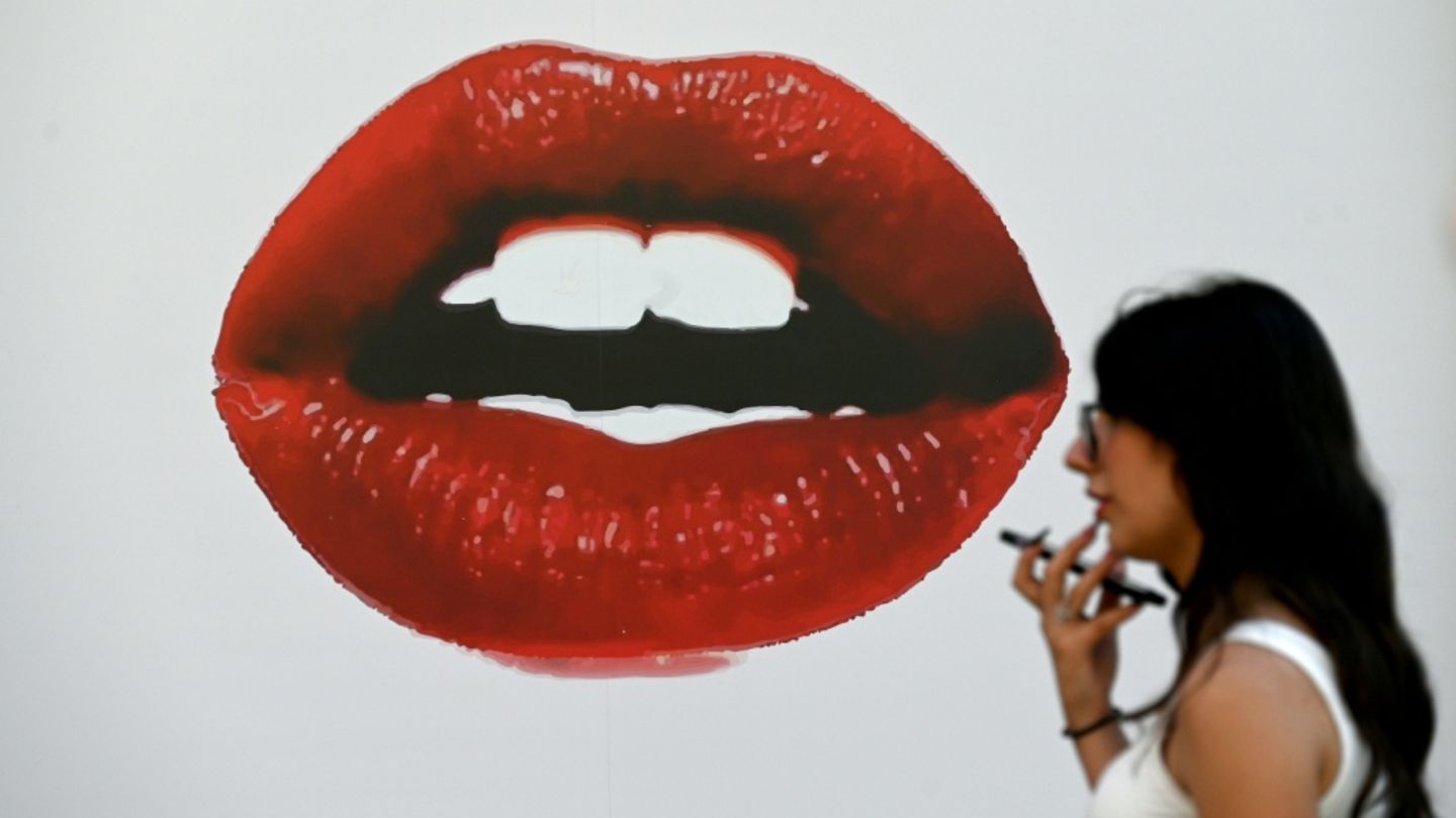 Frau läuft an Plakat mit roten Lippen vorbei