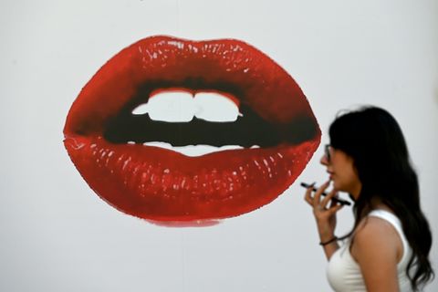 Frau läuft an Plakat mit roten Lippen vorbei