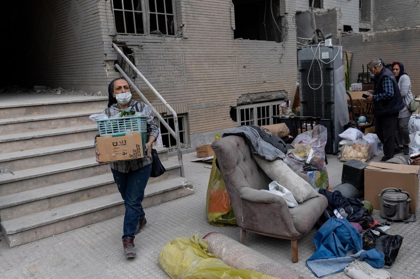 Eine Frau räumt im Osten von Irans Hauptstadt Teheran ihre Habseligkeiten aus ihrem beschädigten Haus