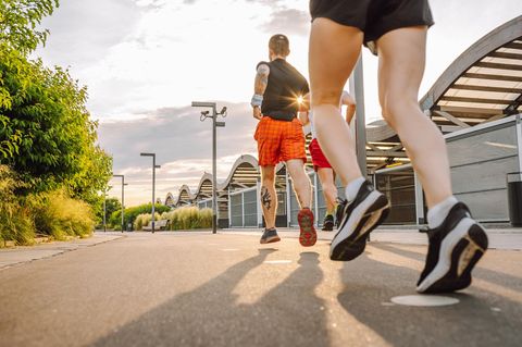 Drei Menschen joggen im Abendlicht durch die Stadt