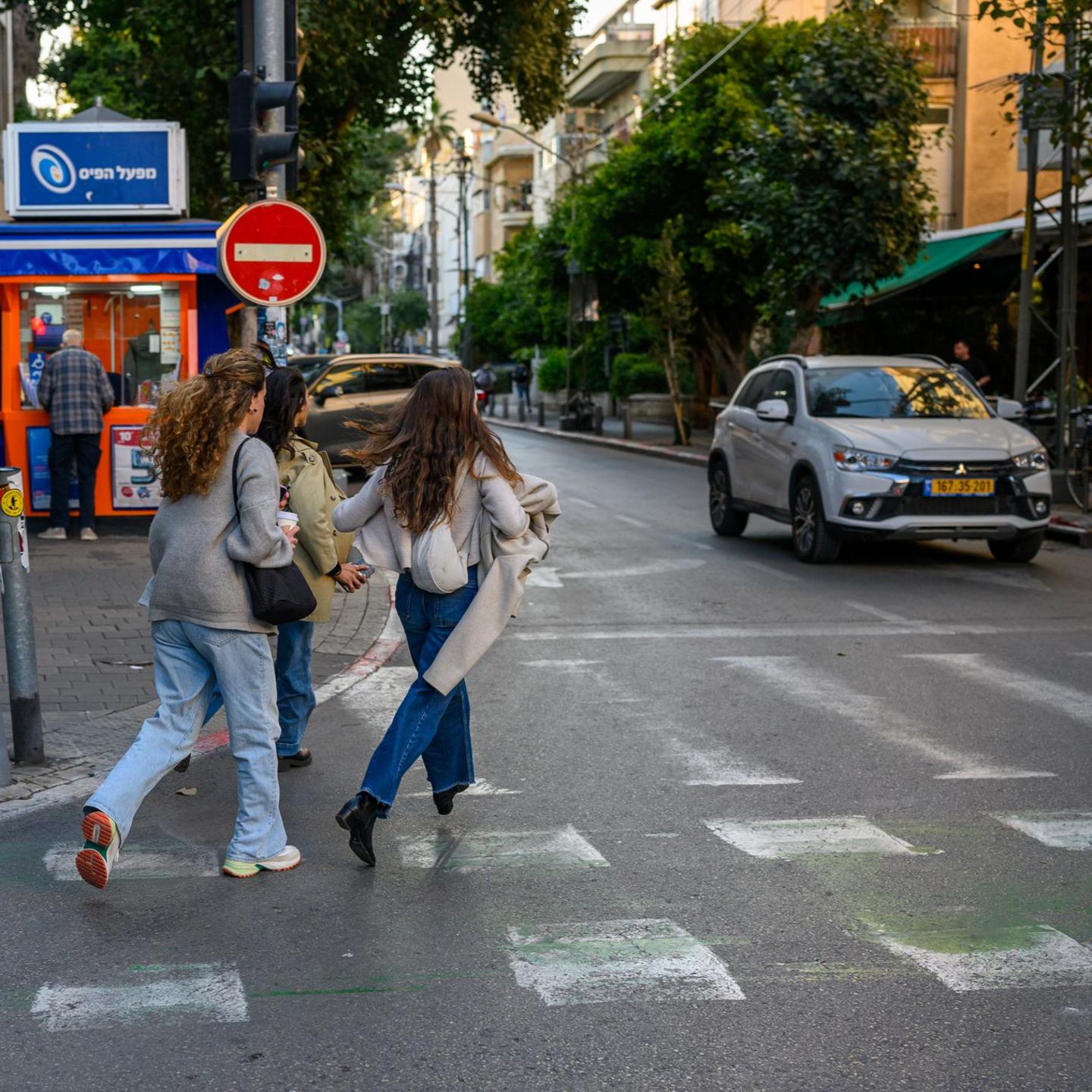 Drei Frauen in Israel laufen auf einer Straße auf den nächsten Schutzraum zu