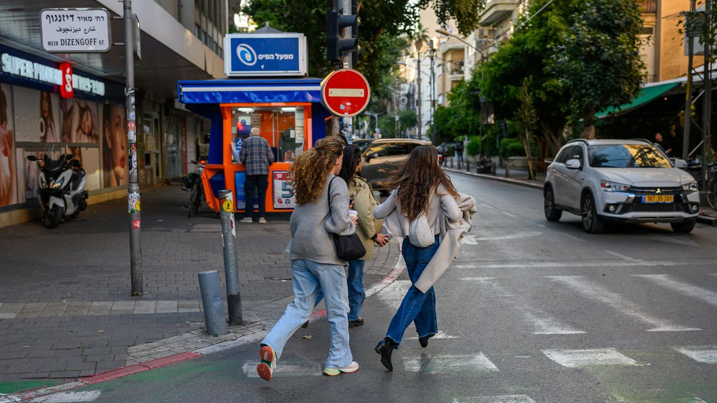 Drei Frauen in Israel laufen auf einer Straße auf den nächsten Schutzraum zu