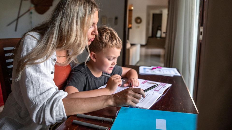 Hilfe bei den Hausgaben: Eine Mutter sitzt mit ihrem Sohn am Schreibtisch