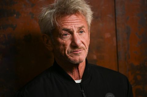 Sean Penn vor einer rostigen Metallwand. Er trägt eine schwarze Jacke.