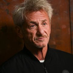 Sean Penn vor einer rostigen Metallwand. Er trägt eine schwarze Jacke.
