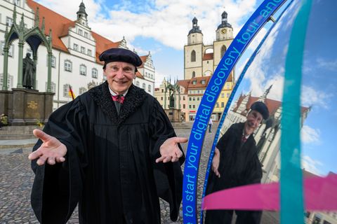 Im Gewand des Martin Luther steht Bernhard Naumann auf dem Marktplatz in Wittenberg. Foto: Hendrik Schmidt/dpa