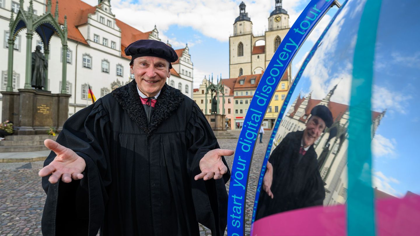 Im Gewand des Martin Luther steht Bernhard Naumann auf dem Marktplatz in Wittenberg. Foto: Hendrik Schmidt/dpa