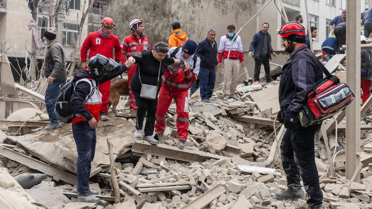 Iranische Rettungskräfte helfen einer Frau aus den Trümmern eines von Israel zerstörten Gebäudes in Teheran