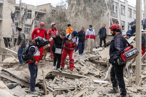 Iranische Rettungskräfte helfen einer Frau aus den Trümmern eines von Israel zerstörten Gebäudes in Teheran