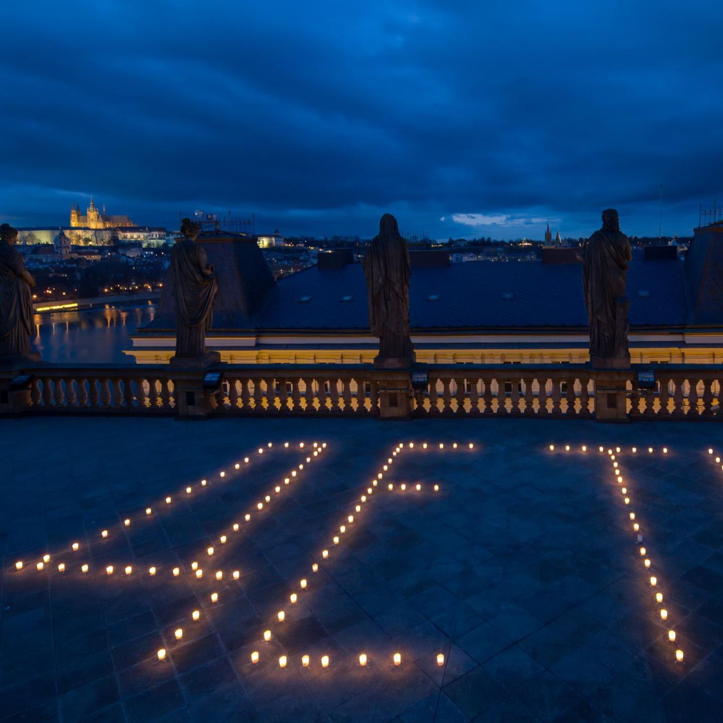 Prag, Tschechien. Kerzen formen das russische Wort für „Kinder“ auf der Dachterrasse des Tschechischen Nationaltheaters. Anlass war der vierte Jahrestag des Beschusses des Theaters von Mariupol in der Ukraine durch russische Streitkräfte – dort stand auf dem Dach das Wort „Kinder“, um Russland von einem Beschuss abzuhalten – vergebens: Mehrere Hundert Menschen starben durch den Luftangriff, die meisten Frauen und Kinder.