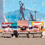 Menschen sonnen sich auf Liegen am Strand