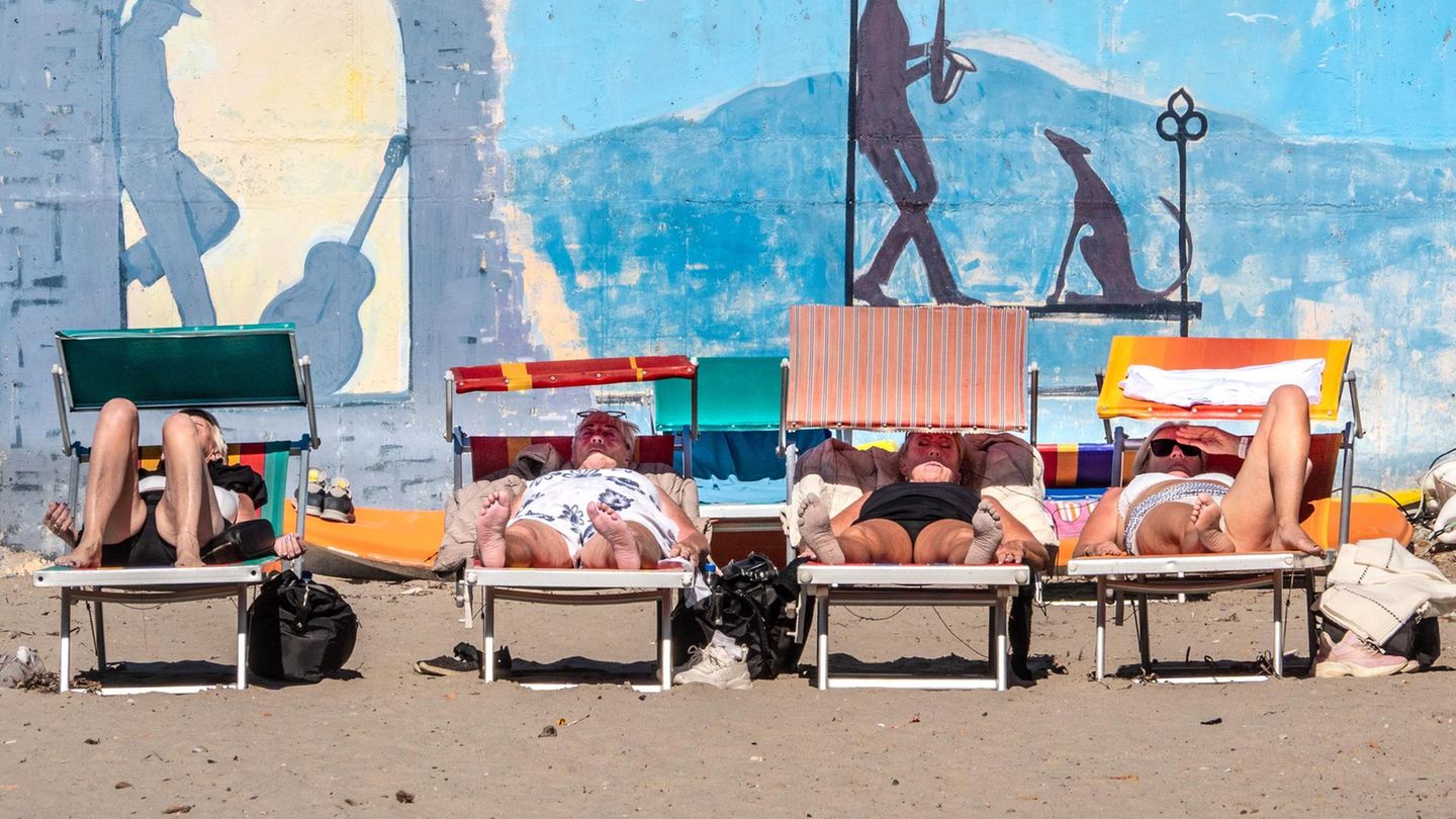 Menschen sonnen sich auf Liegen am Strand