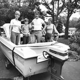 Ein Polizist steht mit Frau und zwei Kindern in einem Boot mit Außenbordmotor