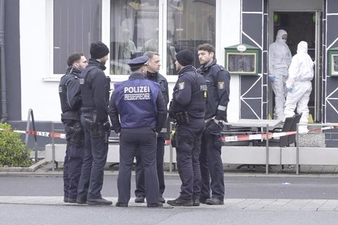 Beamte stehen vor einem Bistro, in dem zwei Menschen ermordet wurden.