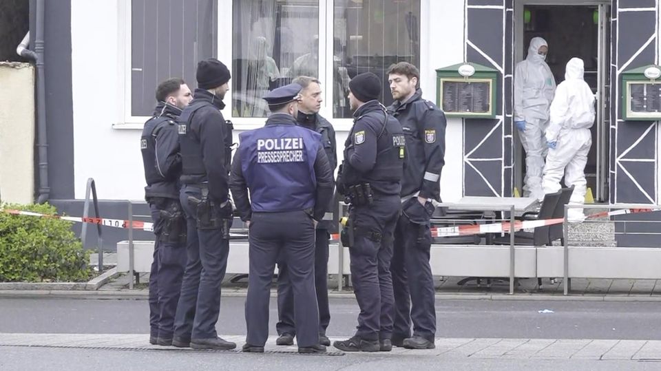 Beamte stehen vor einem Bistro, in dem zwei Menschen ermordet wurden.