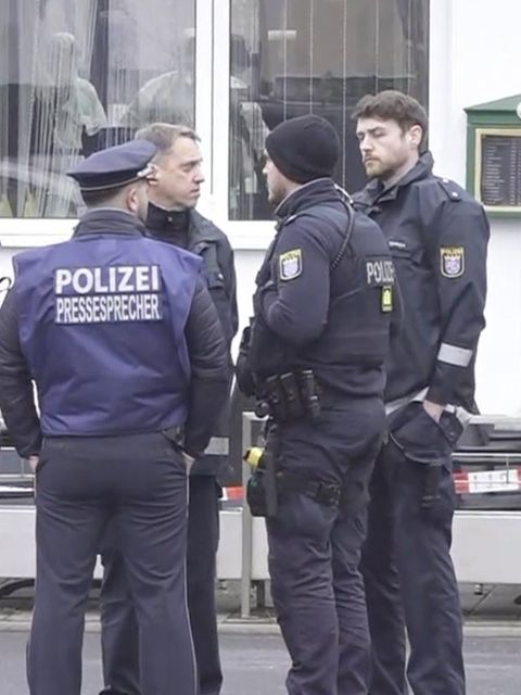 Beamte stehen vor einem Bistro, in dem zwei Menschen ermordet wurden.