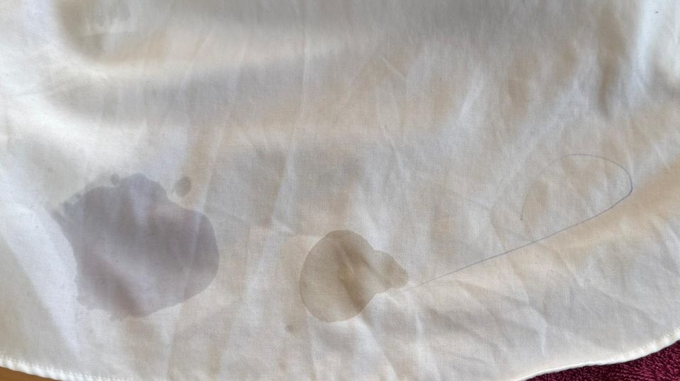 Kaffee-, Schweiß- und Kugelschreiberflecken auf weißem Stoff