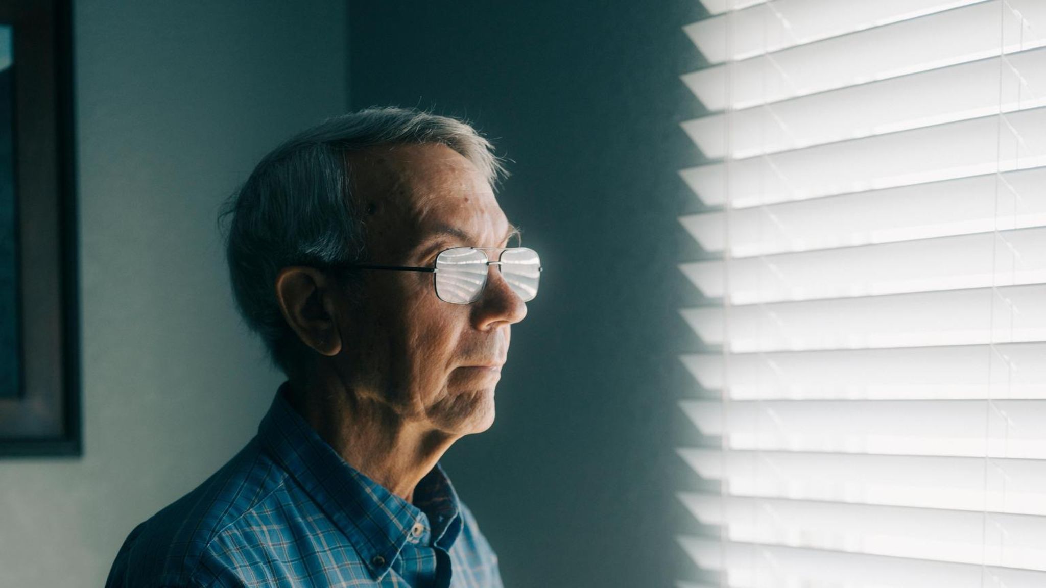 David Kaczynski blickt aus einem mit einer Jalousie verhängten Fenster