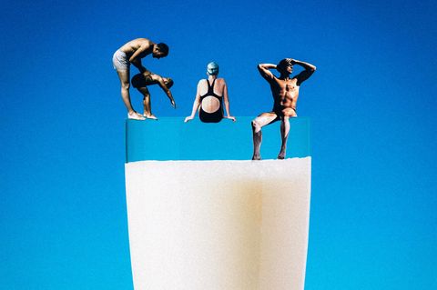 Montage: Kleine Menschen sitzen am Rand eines Milchglases, sie sind in Bademode gekleidet.