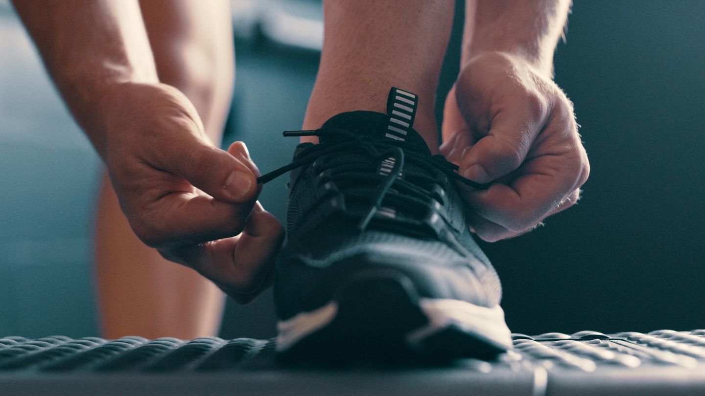 Ratgeber Hyrox Schuhe: Mann schnürt Sportschuhe