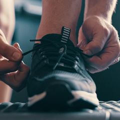 Ratgeber Hyrox Schuhe: Mann schnürt Sportschuhe