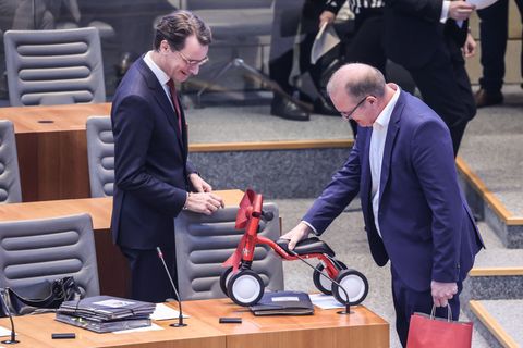 Jochen Ott (SPD, r.) überreicht Hendrik Wüst (CDU) das 1. FC-Köln-Laufrad im Plenarsaal des Landtags. Foto: Oliver Berg/dpa