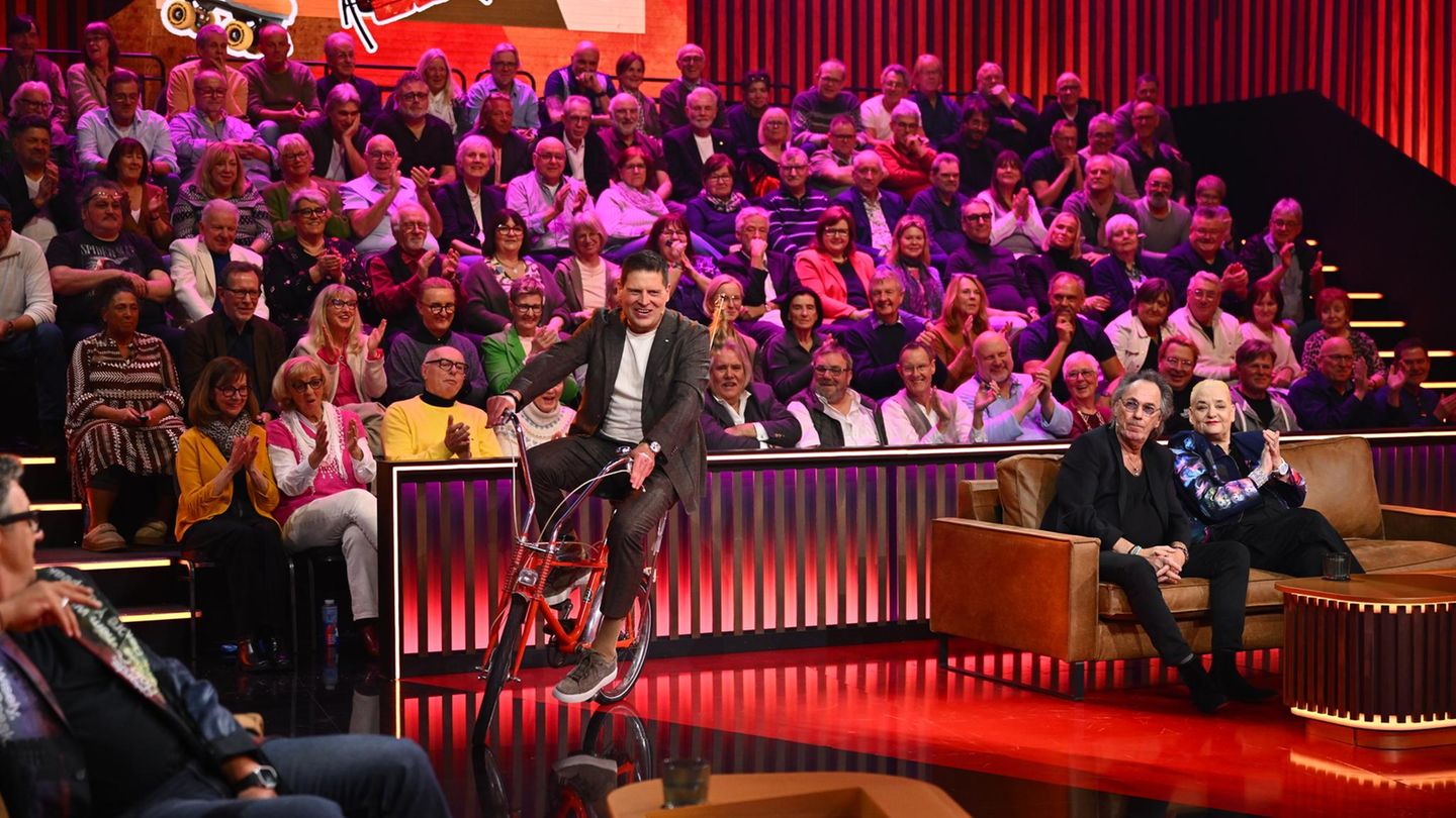 Jan Ullrich fährt auf einem Fahrrad durch ein TV-Studio