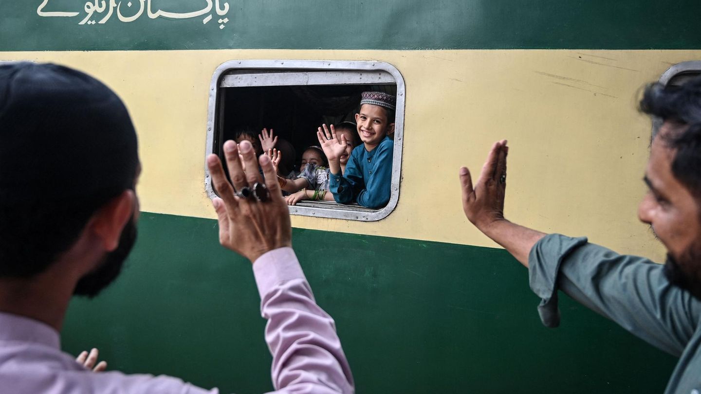 Karatschi, Pakistan. Kinder winken aus dem Zugfenster ihren Familienangehörigen. Der Zug ist voll von Menschen, die wegen des Fastenbrechens am Ende des Fastenmonats Ramadan ab dem 20. März nach Hause fahren. In einigen Regionen wird dieses Fest Zuckerfest genannt.