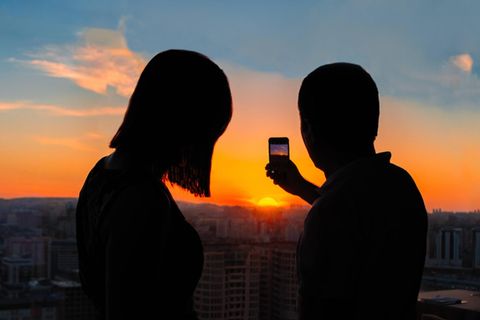 Ein Paar fotografiert einen Sonnenuntergang