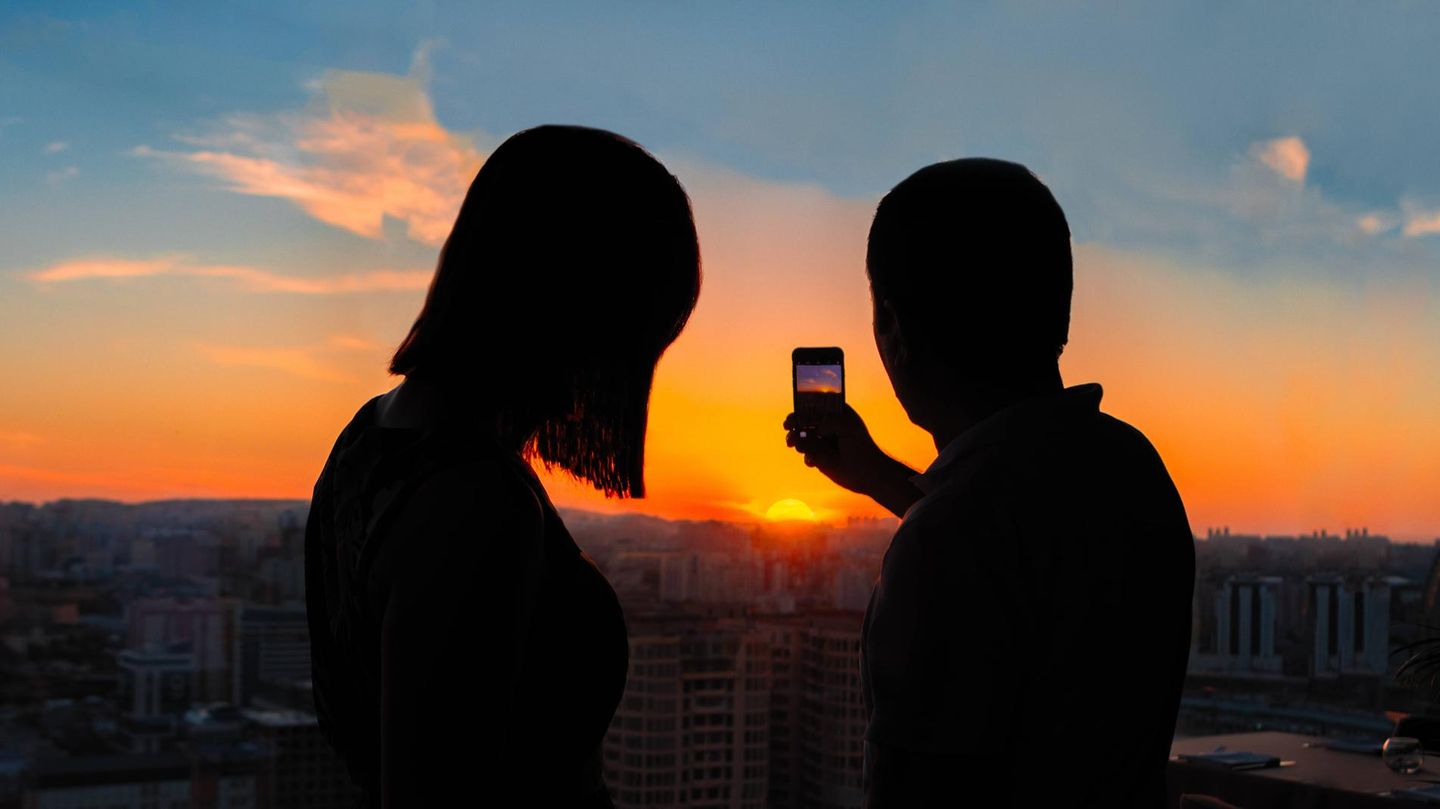 Ein Paar fotografiert einen Sonnenuntergang
