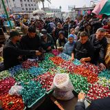 Gaza-City, Gaza. Palästinenser versammeln sich um einen Verkaufsstand, um sich mit Süßigkeiten für Eid al-Fitr, das Fastenbrechen am Ende des Ramadans, einzudecken. Die Lage ist für die Menschen etwas besser geworden, aber das Leben bleibt schwierig. Die israelische Armee hält weiterhin fast 60 Prozent des schmalen Küstenstreifens besetzt.