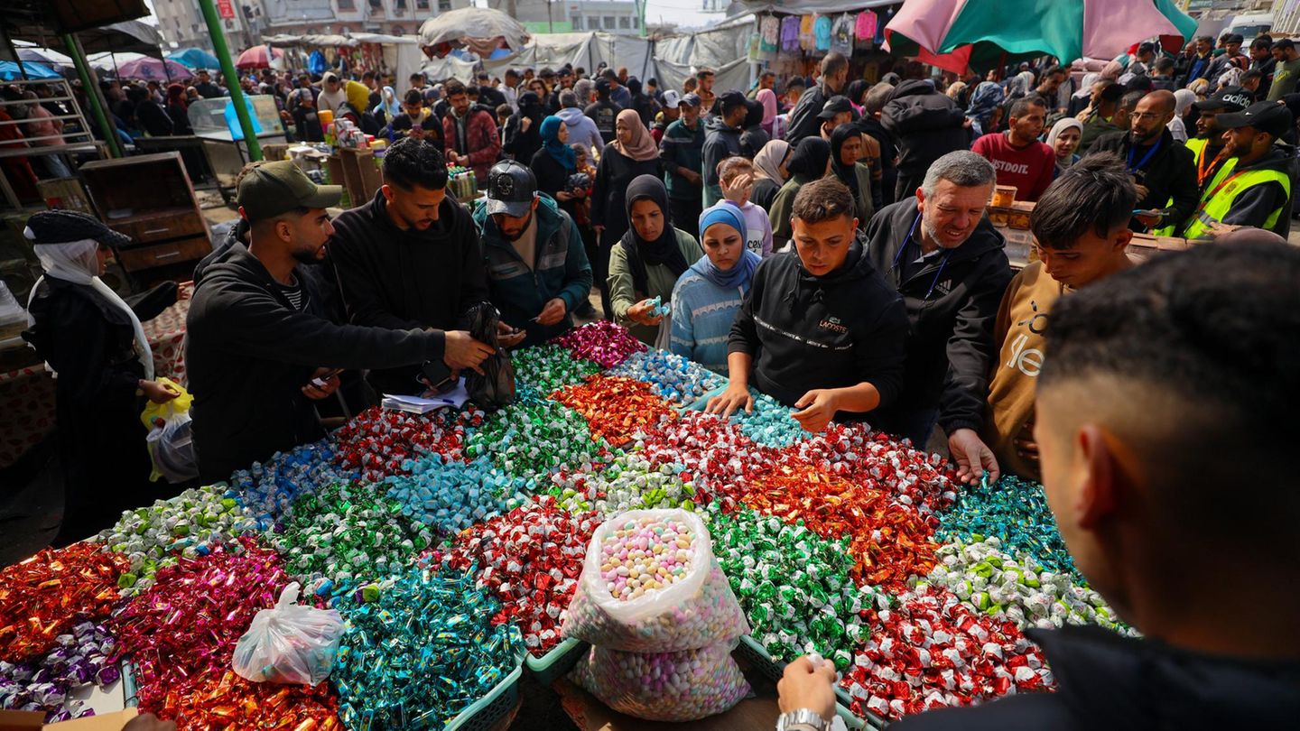 Gaza-City, Gaza. Palästinenser versammeln sich um einen Verkaufsstand, um sich mit Süßigkeiten für Eid al-Fitr, das Fastenbrechen am Ende des Ramadans, einzudecken. Die Lage ist für die Menschen etwas besser geworden, aber das Leben bleibt schwierig. Die israelische Armee hält weiterhin fast 60 Prozent des schmalen Küstenstreifens besetzt.