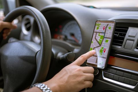 Fahrer mit GPS-Navigation im Handy während der Fahrt Auto
