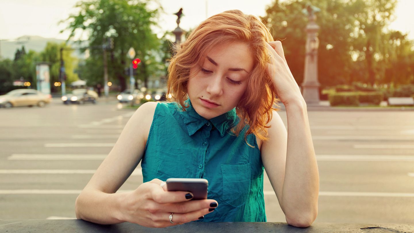 Eine Frau schaut frustriert auf ihr iPhone