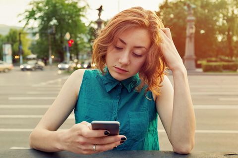 Eine Frau schaut frustriert auf ihr iPhone