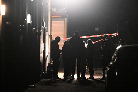 Polizeibeamte, Kriminalpolizei, Spurensicherung und Staatsanwaltschaft stehen vor einem Haus, in dem eine Frau tot aufgefunden w