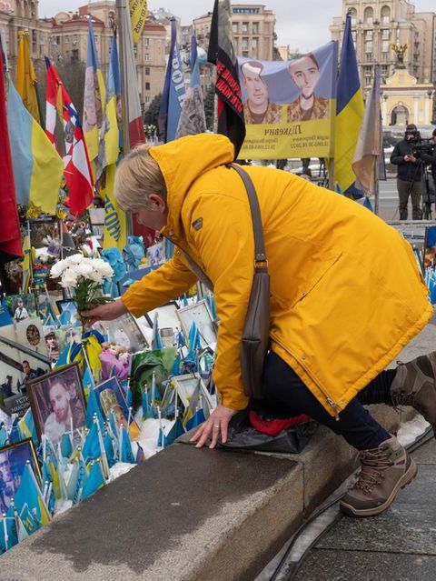 Eine Frau legt Blumen vor dem Denkmal für den gefallenen Soldaten in Kiew ab