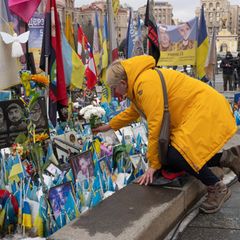 Eine Frau legt Blumen vor dem Denkmal für den gefallenen Soldaten in Kiew ab
