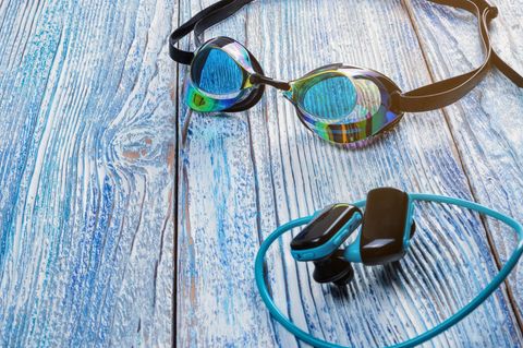 Knochenschall-Kopfhörer liegen neben einer Schwimmbrille