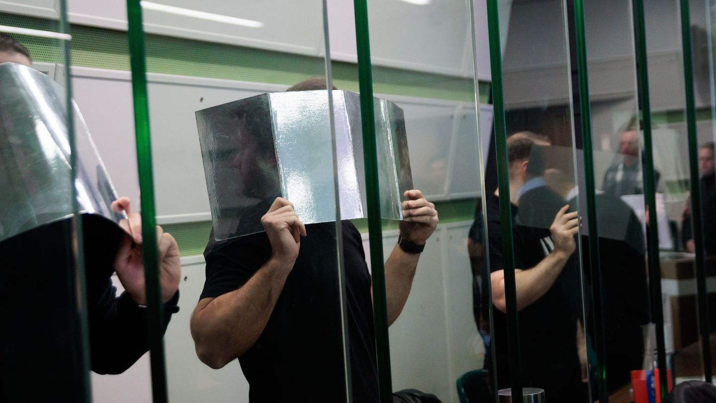 Angeklagte verdecken ihre Gesichter im Gerichtssaal beim Prozess wegen mehrerer Fahrzeugbrände. (Archivbild) Foto: Carsten Koall