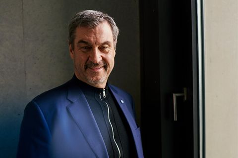 Markus Söder schaut in die Kamera, hinter einer Scheibe sieht man den CSU-Schriftzug