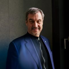 Markus Söder schaut in die Kamera, hinter einer Scheibe sieht man den CSU-Schriftzug