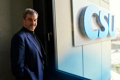 Markus Söder schaut in die Kamera, hinter einer Scheibe sieht man den CSU-Schriftzug