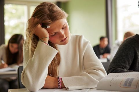 Eine müde Schülern stützt ihren schweren Kopf