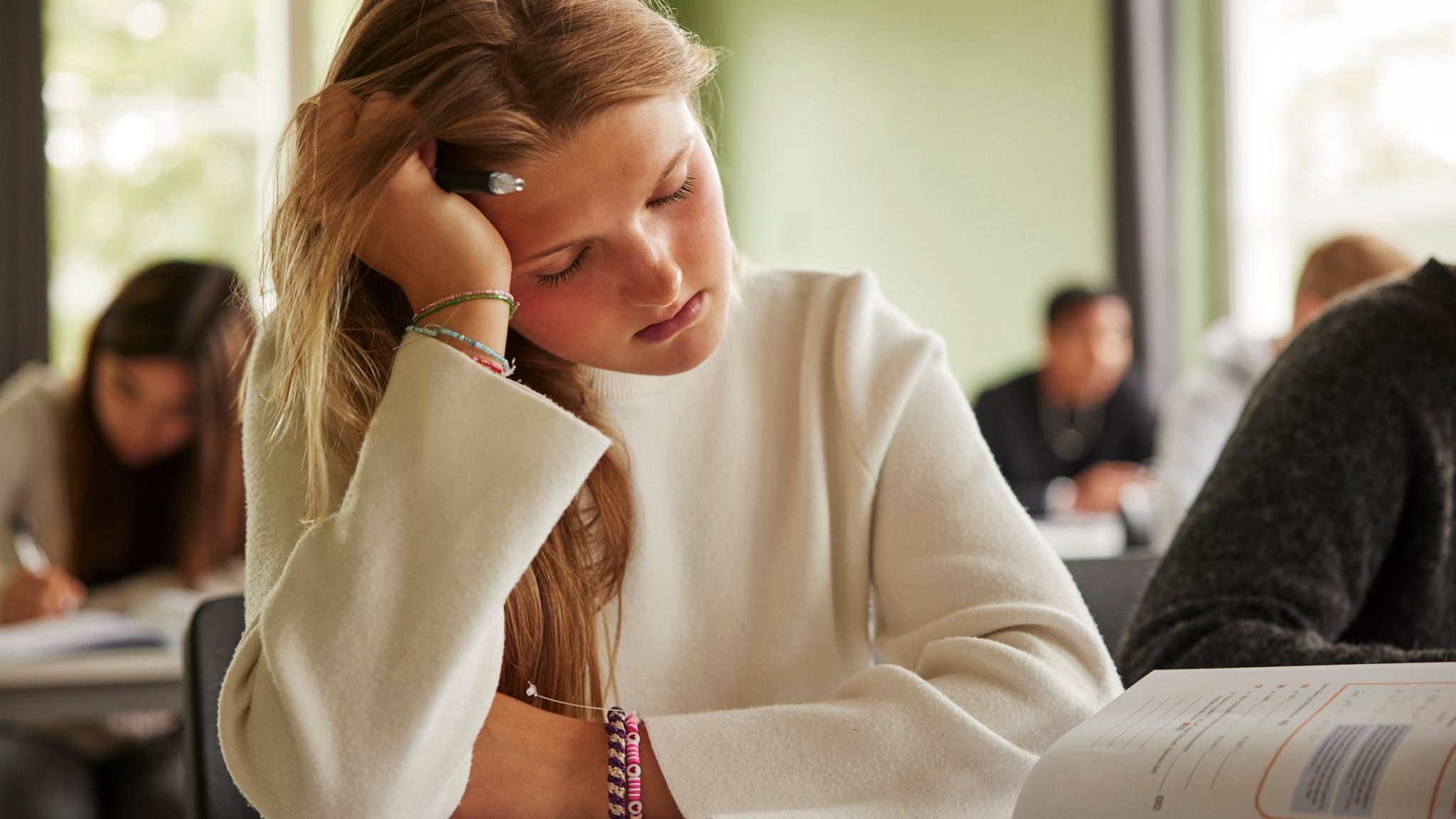 Eine müde Schülern stützt ihren schweren Kopf