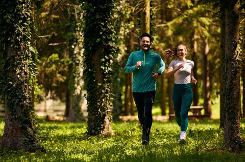 Jogging-Outfit im Frühling: Junges Pärchen beim Joggen im Wald