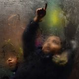 Kind im Bus zeichnet mit dem Finger auf beschlagene Scheibe