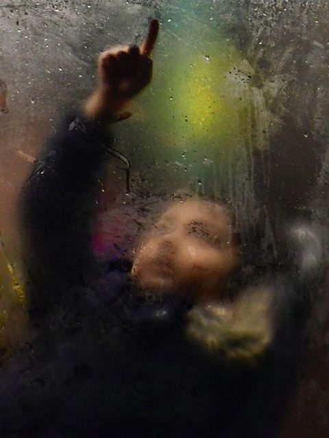 Kind im Bus zeichnet mit dem Finger auf beschlagene Scheibe